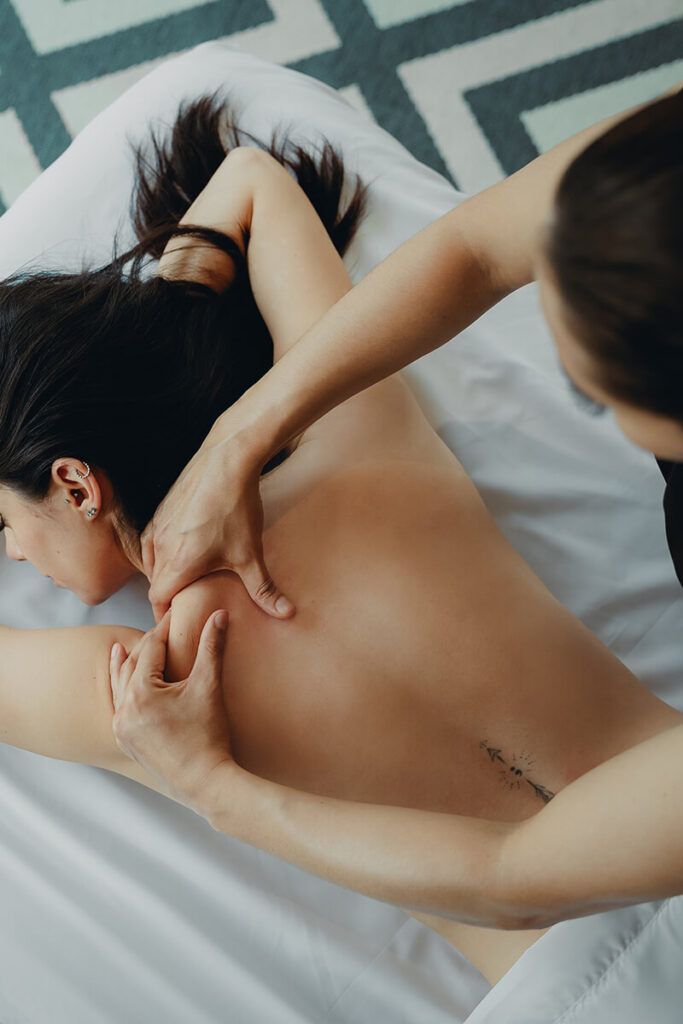 Mujer recibiendo un masaje de espalda en una mesa de masajes; las manos del terapeuta en su espalda, aplicando presión.