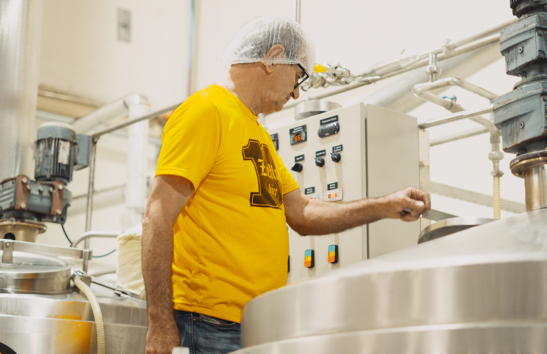 Um homem de camisa amarela está trabalhando em uma fábrica.