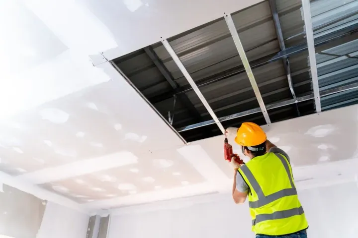 Contractor installing a drywall ceiling.