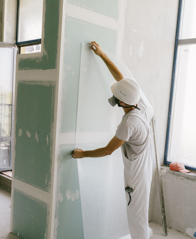 Worker hanging a drywall sheet.