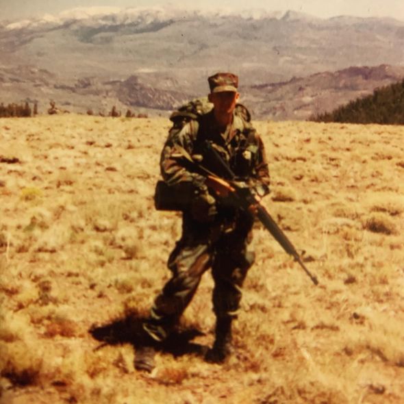 A man with a backpack is standing on top of a rocky cliff.