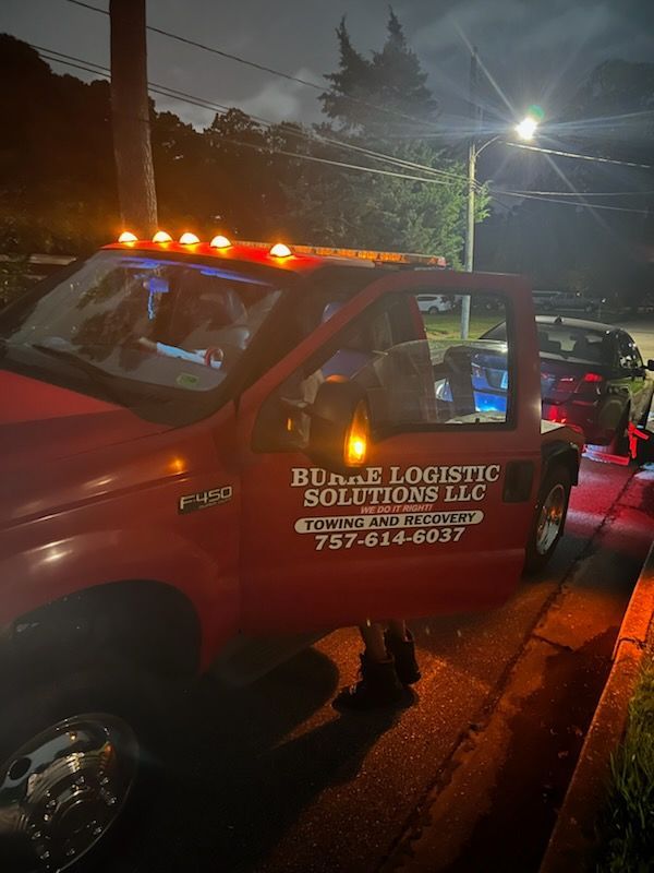 A red truck is parked on the side of the road at night.