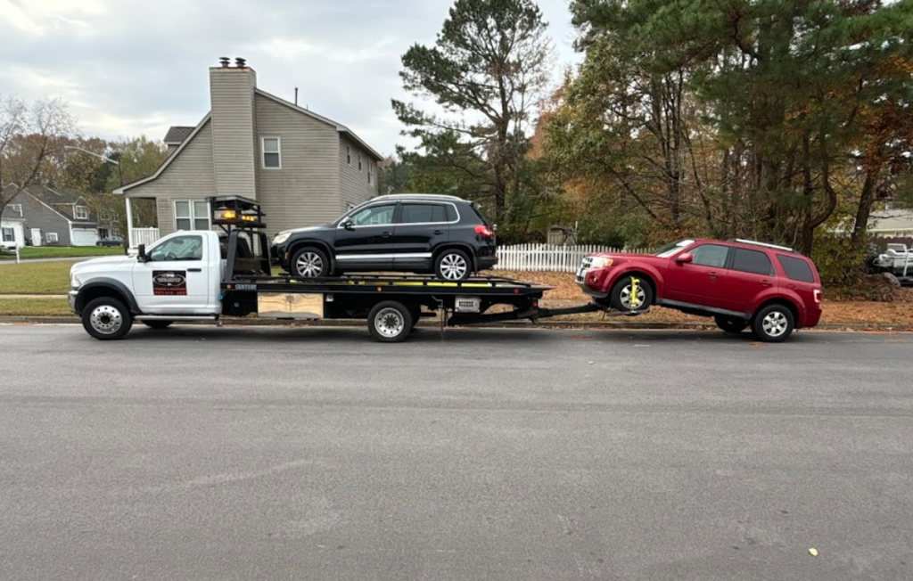 Two cars are being towed by a tow truck.