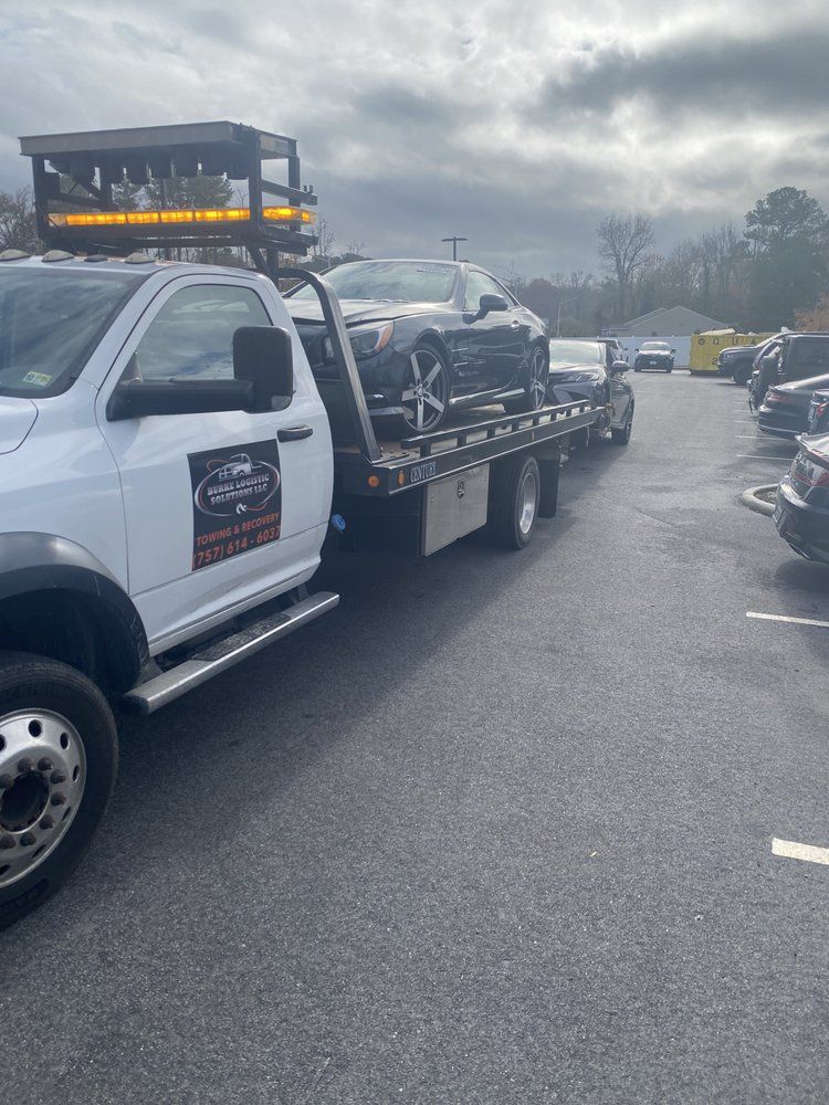 A tow truck is towing a car in a parking lot.