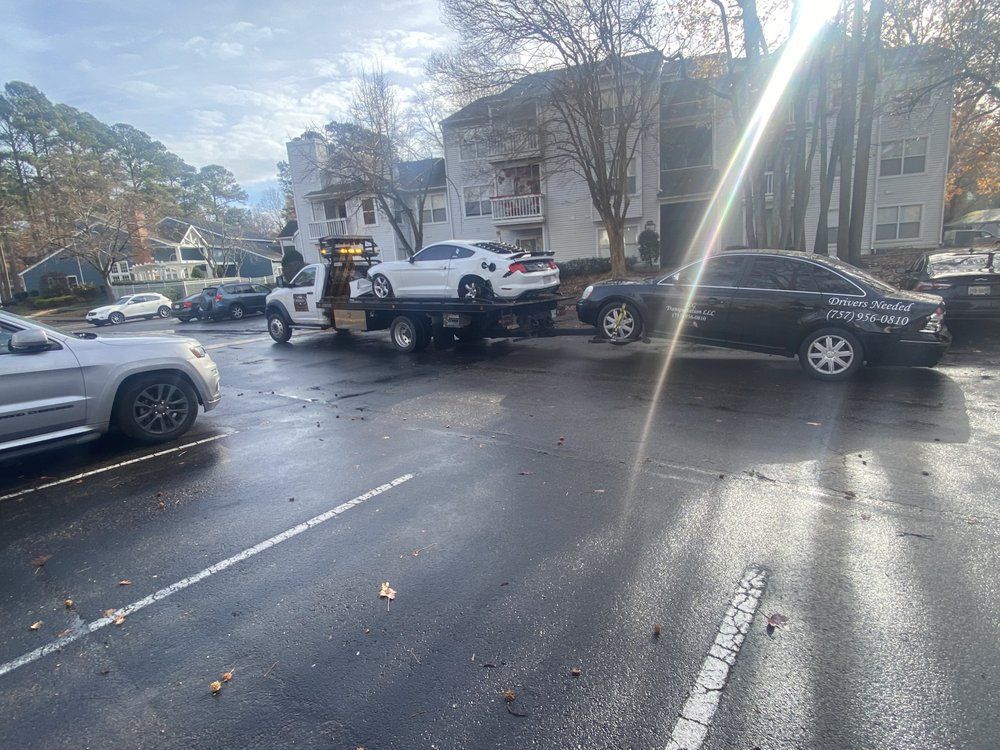 A tow truck is towing a car in a parking lot.
