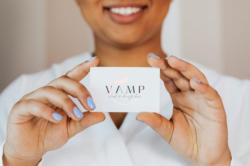 Person holding a white card labeled “VAMP” and smiling in a white top