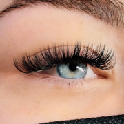 Close-up of a blue eye with long black eyelashes and neatly groomed eyebrow