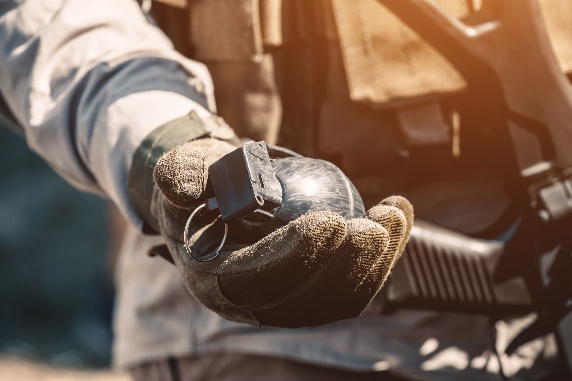 Gloved hand holding a vehicle key near a motorcycle, with warm sunlight in the background