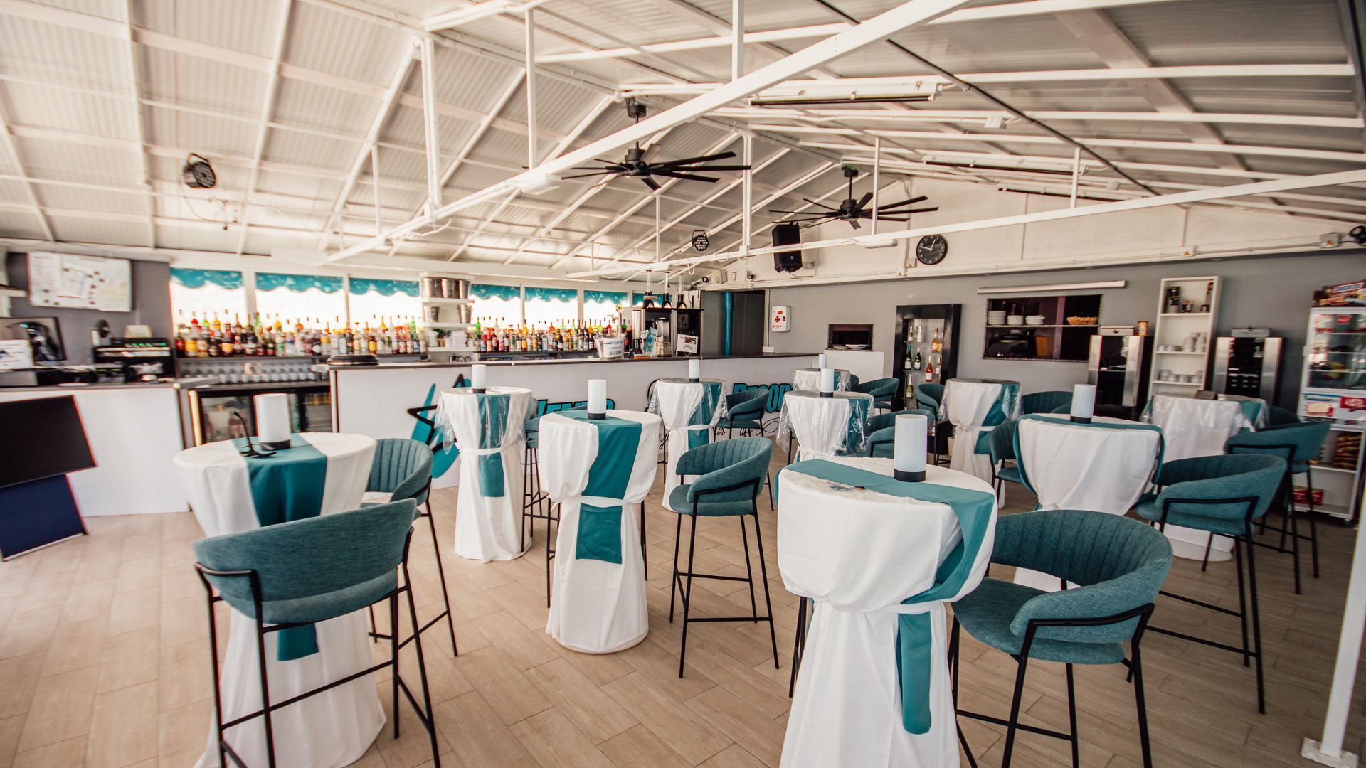 Bright modern restaurant dining room with teal chairs and white tablecloths set for guests