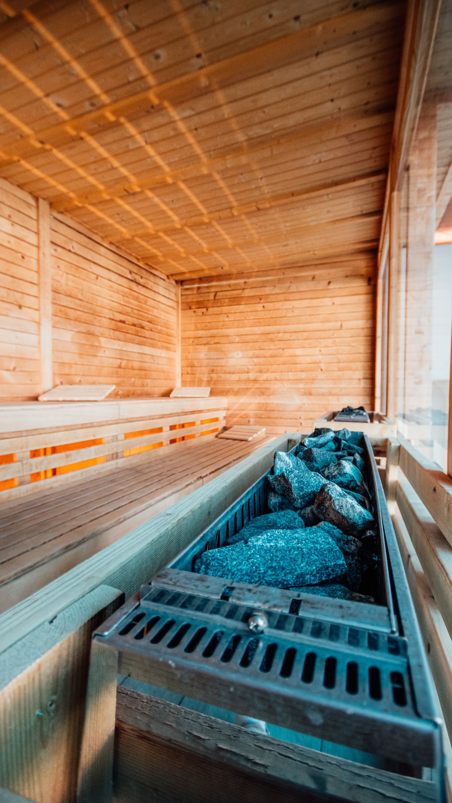 Wooden sauna room with benches and a central heater filled with stones and coals.