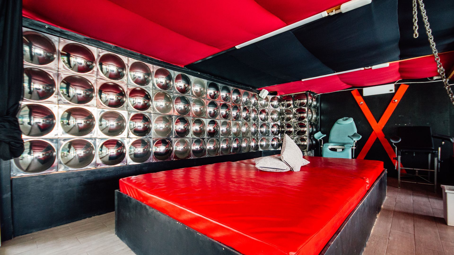 Red-and-black modern lounge with mirrored wall, glossy red table, and geometric decor