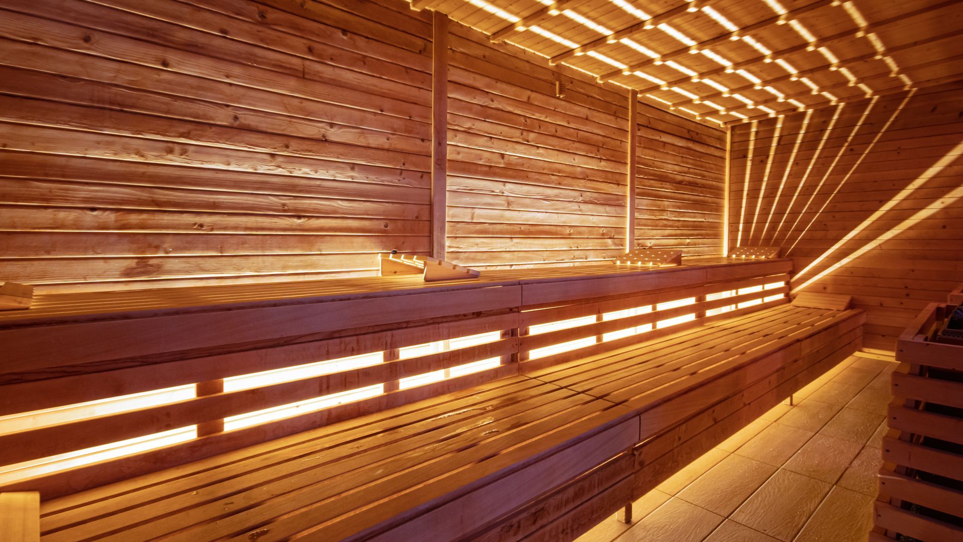 Wooden sauna interior with warm amber lighting and slatted benches along the walls