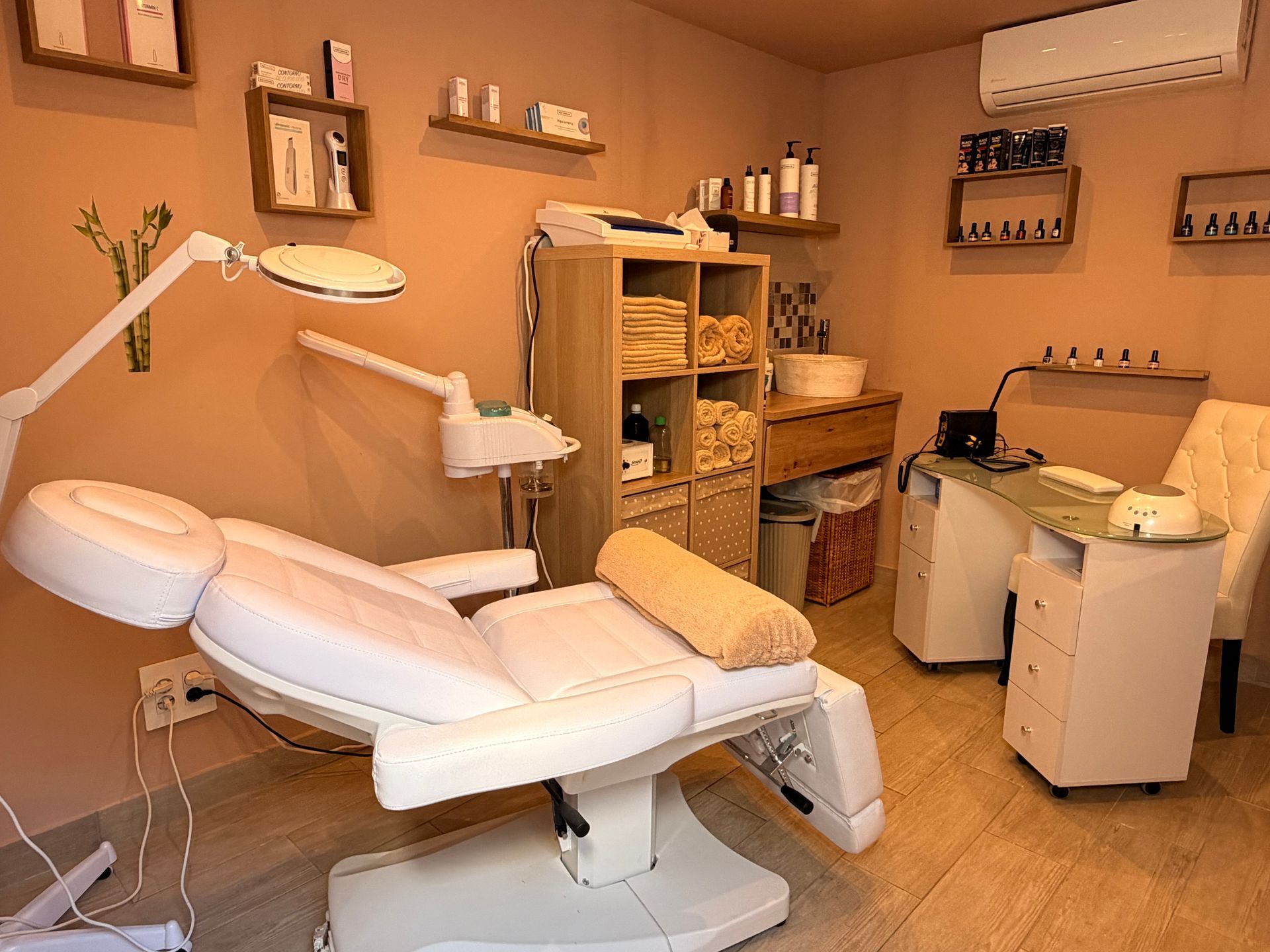 Spa treatment room with a white reclining chair, shelves, and skincare equipment on beige walls