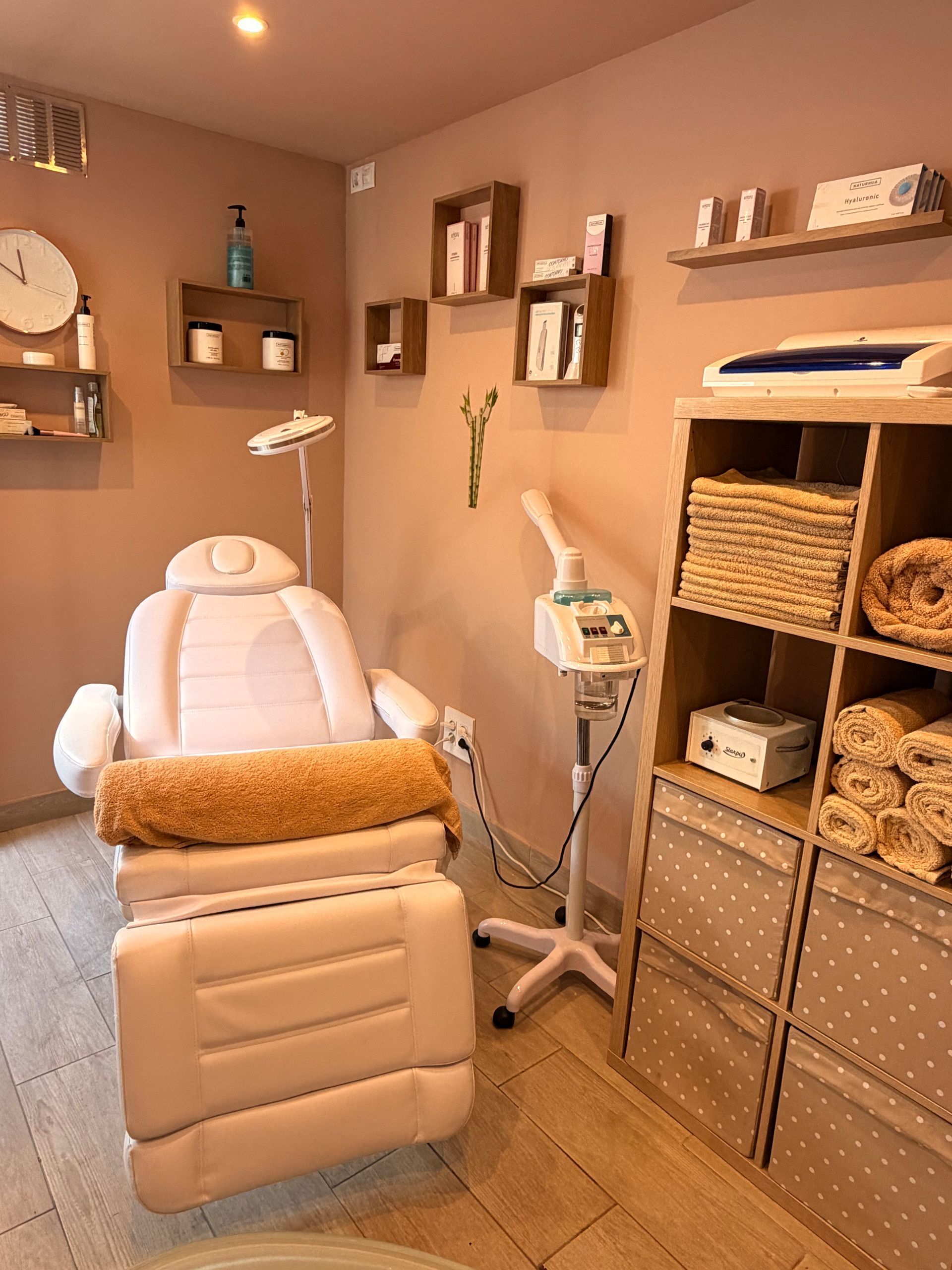Spa treatment room with a white massage chair, shelves, and woven storage baskets