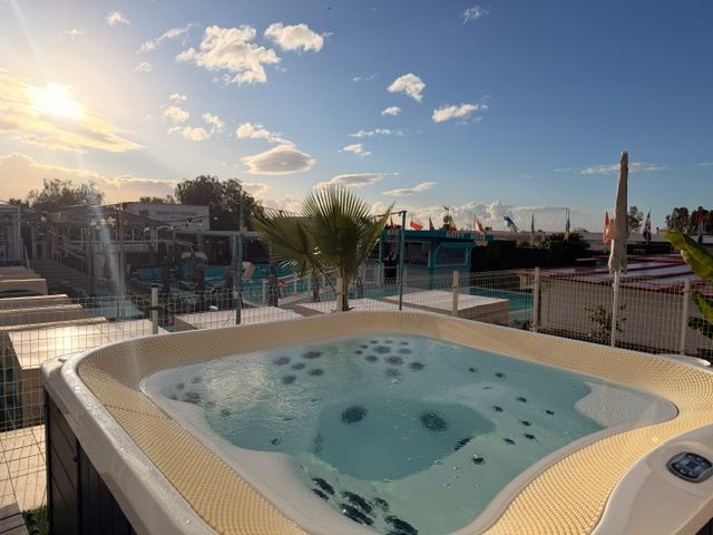 Rooftop hot tub with clear water and city skyline at sunset.