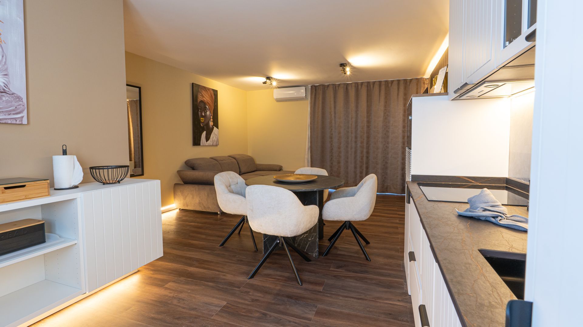 Cozy studio apartment with kitchen, dining table, sofa, and warm lighting