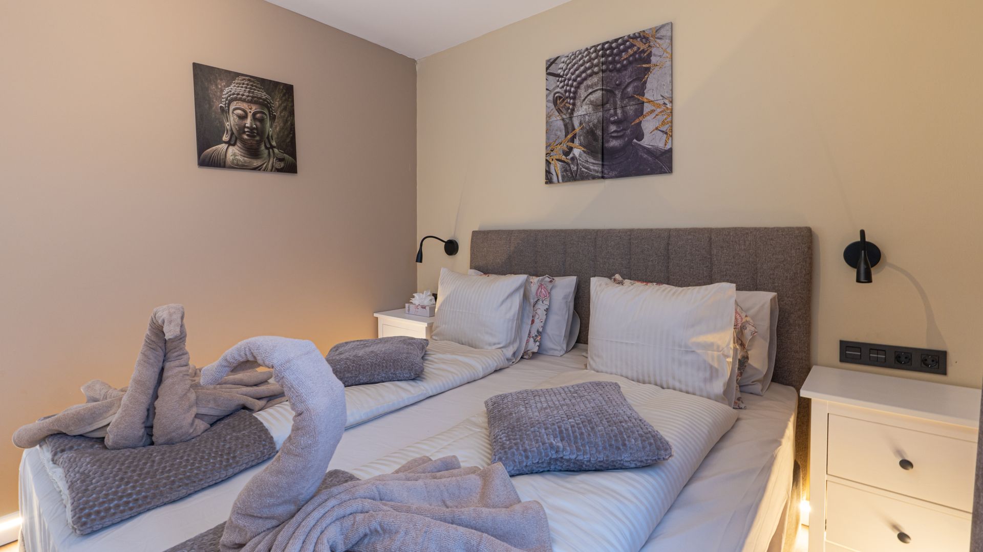 Neat bedroom with a bed made in gray and white bedding, bedside table, and wall art above the headboard