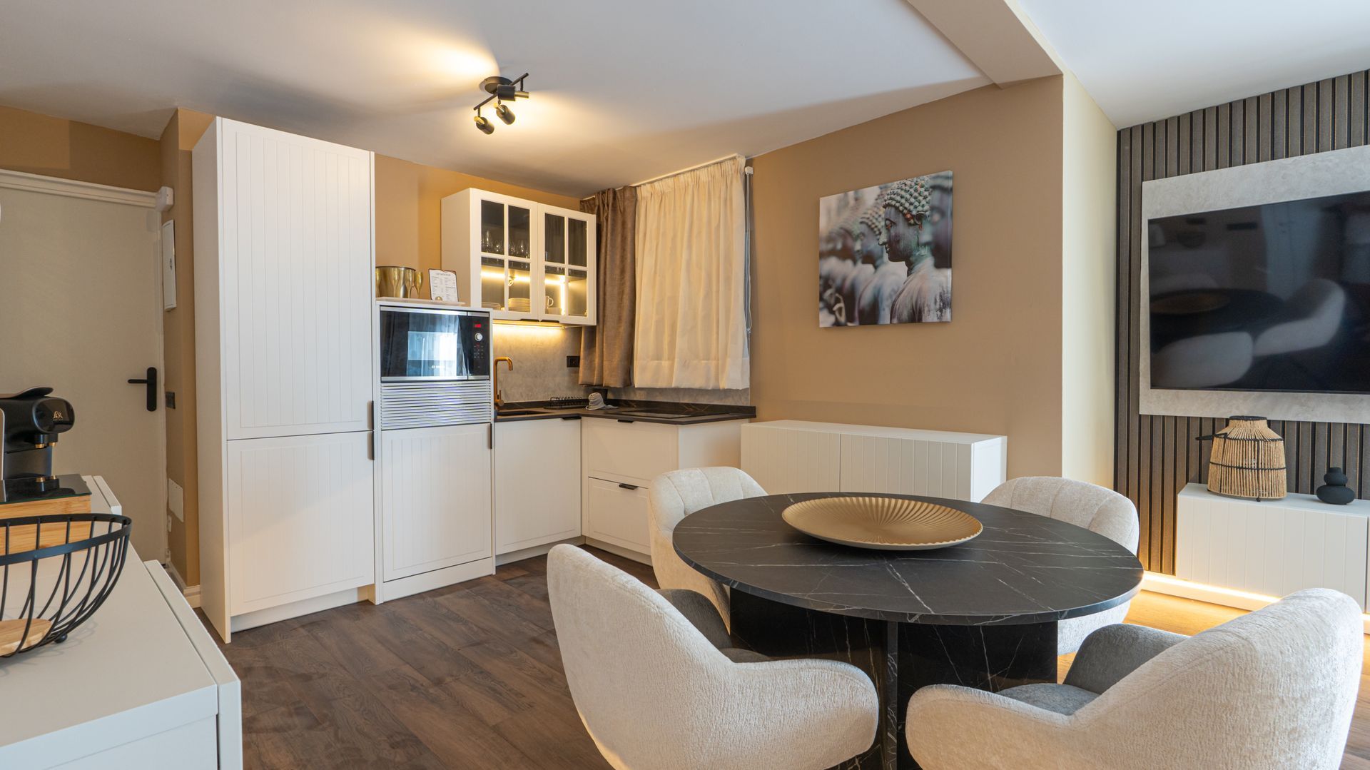 Bright modern kitchen and dining area with white cabinets, round table, and wall art