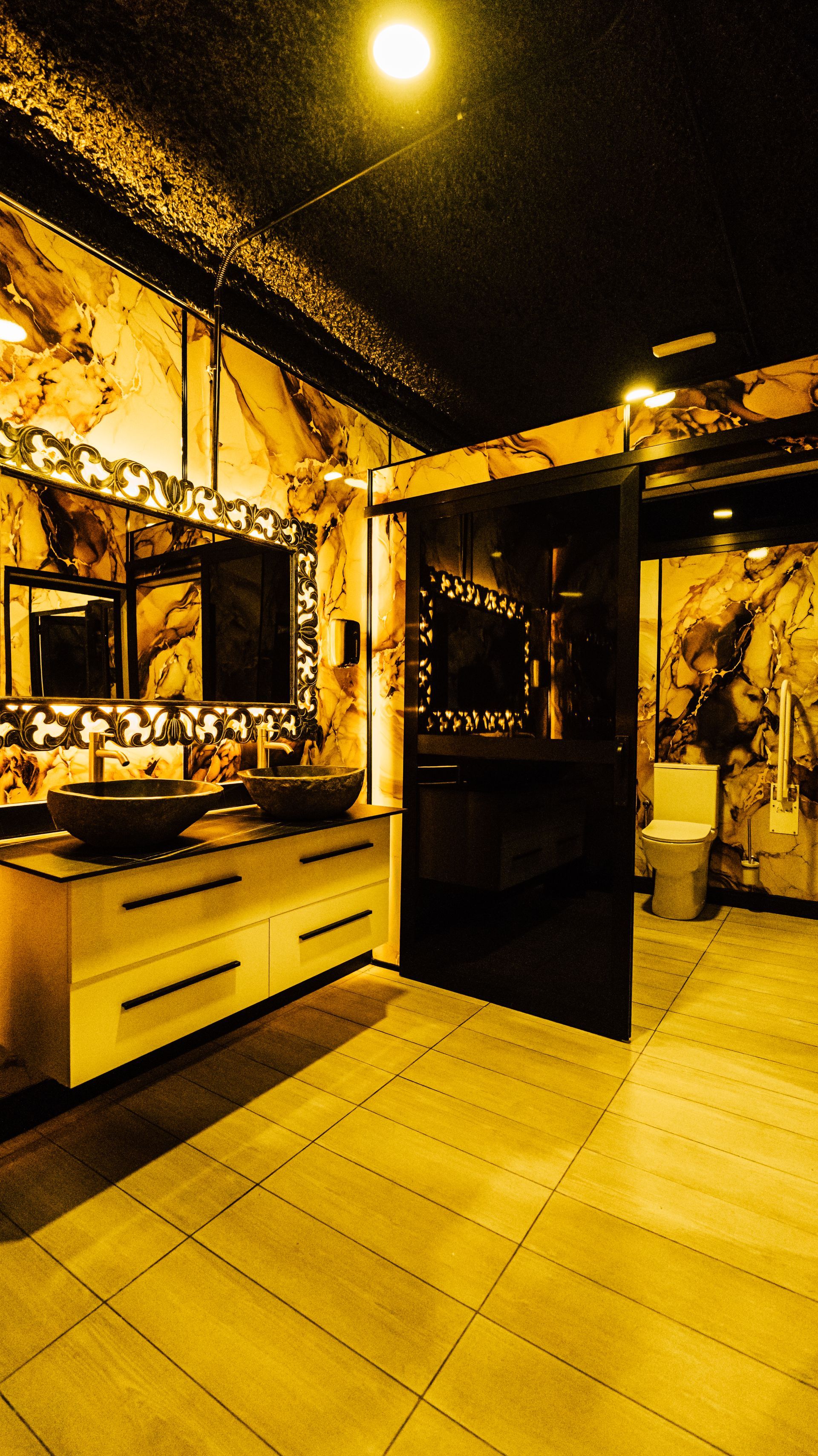 Warm yellow-toned salon interior with mirrors, styling chairs, and tiled floor