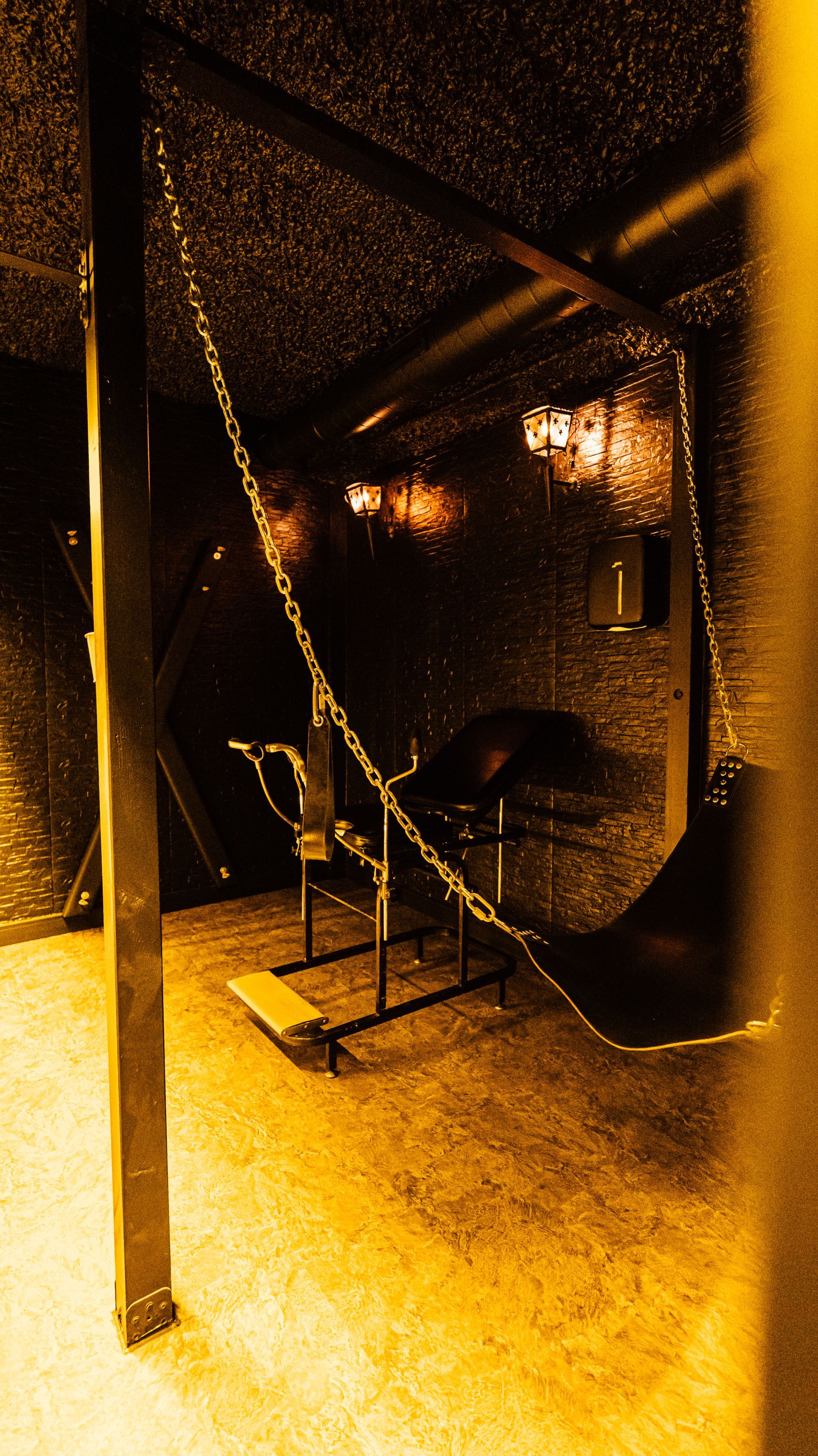 A dim industrial stairwell with metal steps, rails, and warm yellow lighting.
