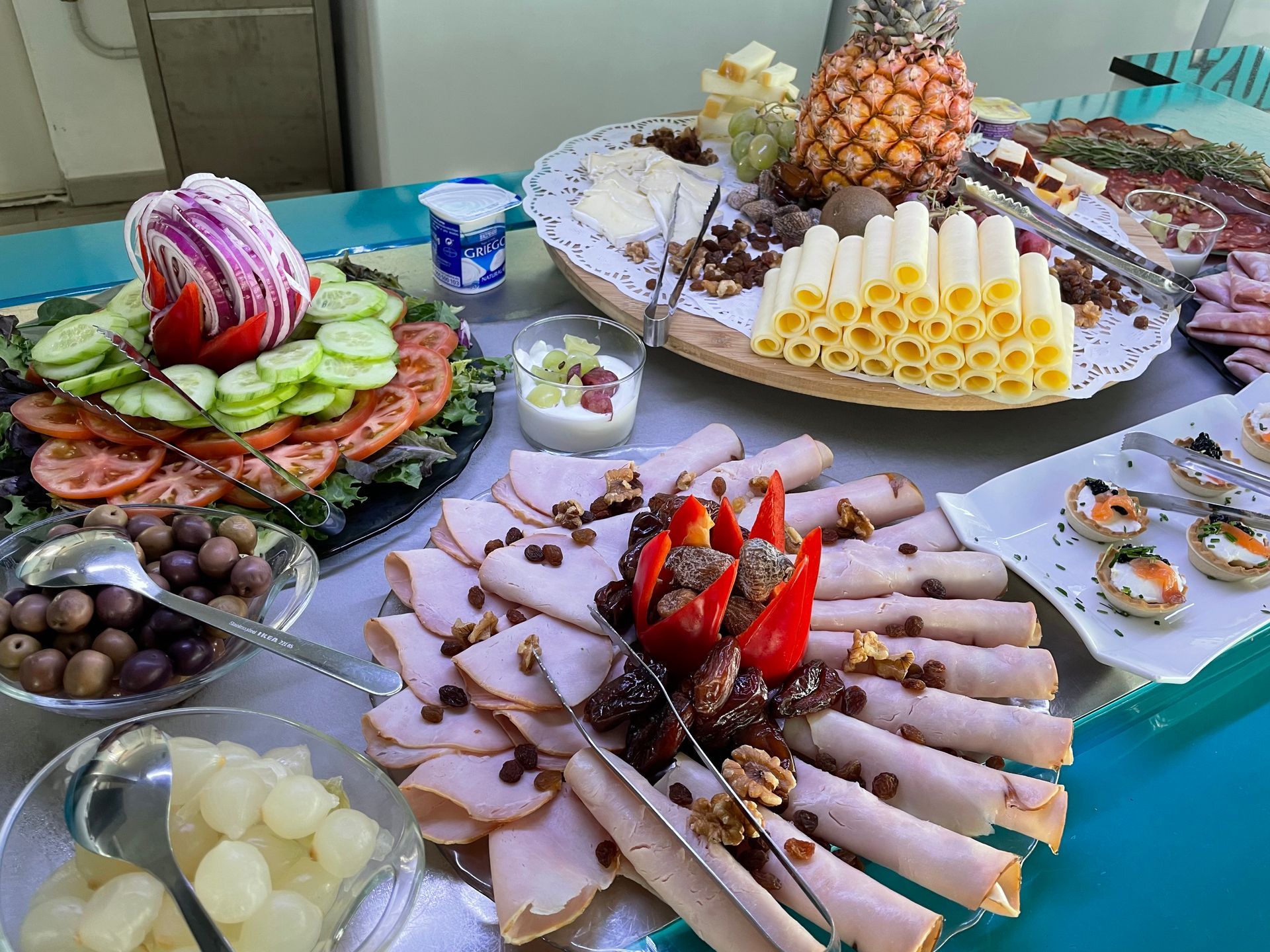 Buffet table with assorted sliced meats, fruit, pastries, and desserts arranged on platters