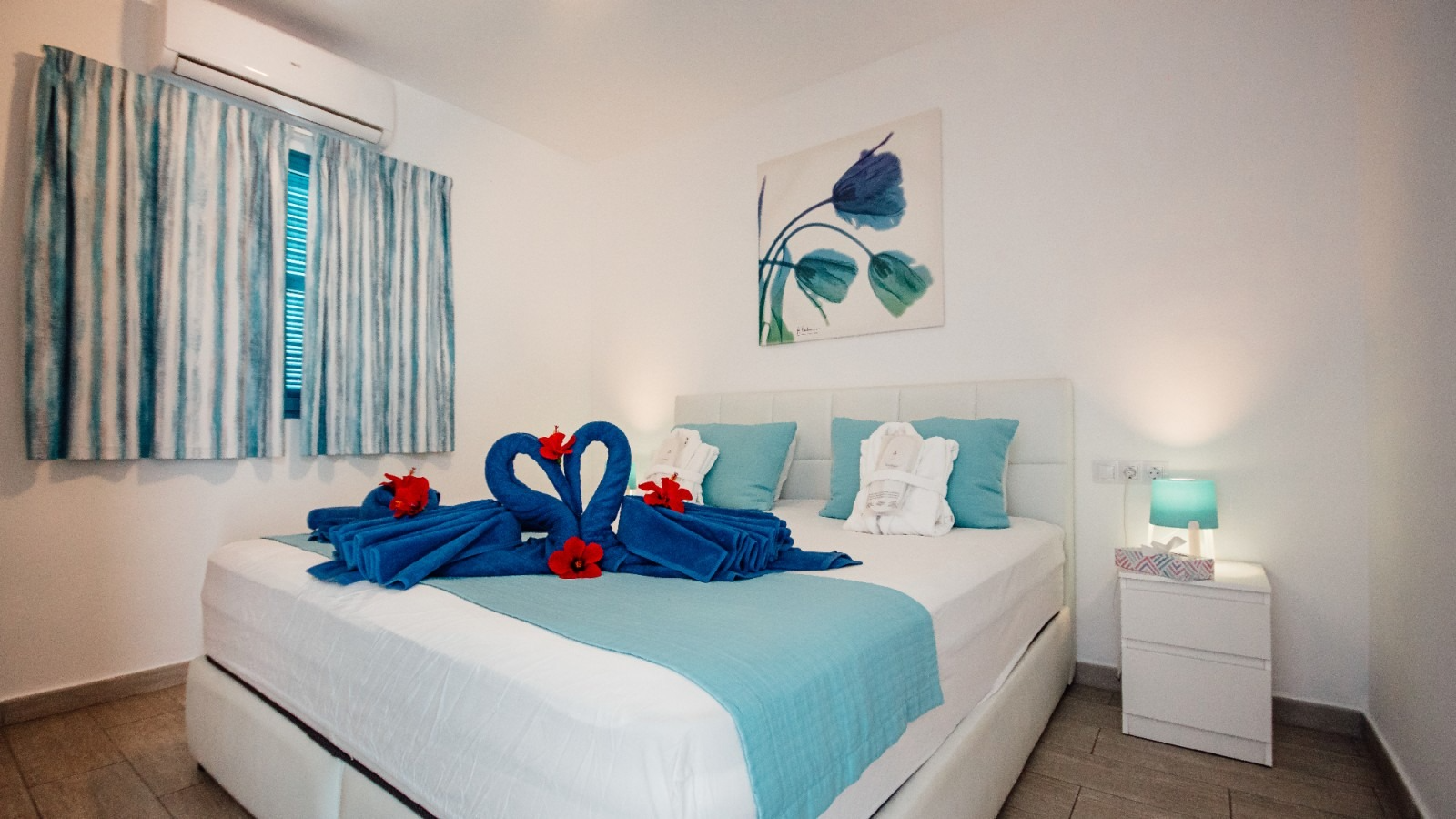 Bright bedroom with a white bed, blue accents, and towel swans on the bed