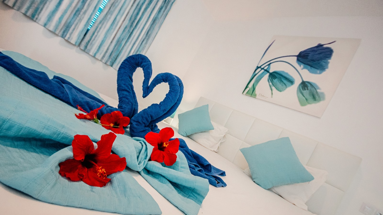Blue-and-white bedroom decor with red flowers and heart-shaped towels on a bed