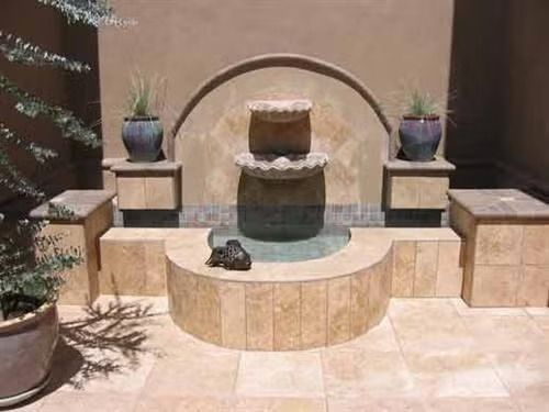 A stone retaining wall built along a water feature, backed by a lush, green hedge.