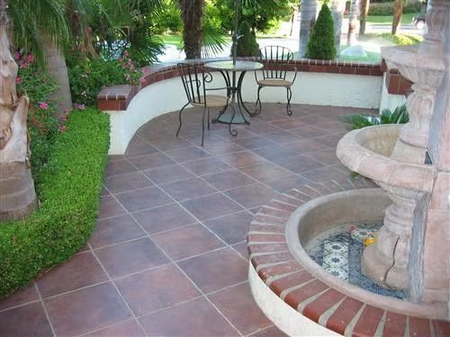 Patio with tiled floor, two metal chairs and table, curved bench wall, and a small fountain on the right