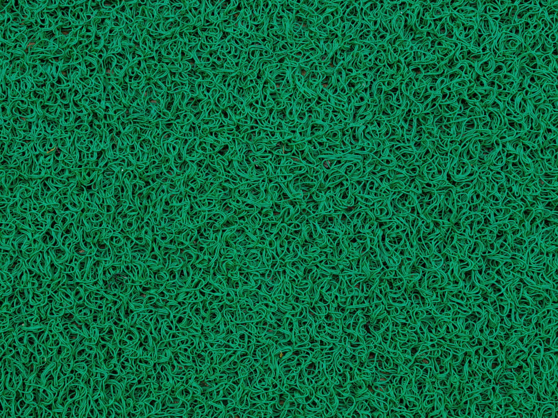 A textured, dark green coil floor mat with a dense, looped vinyl surface.