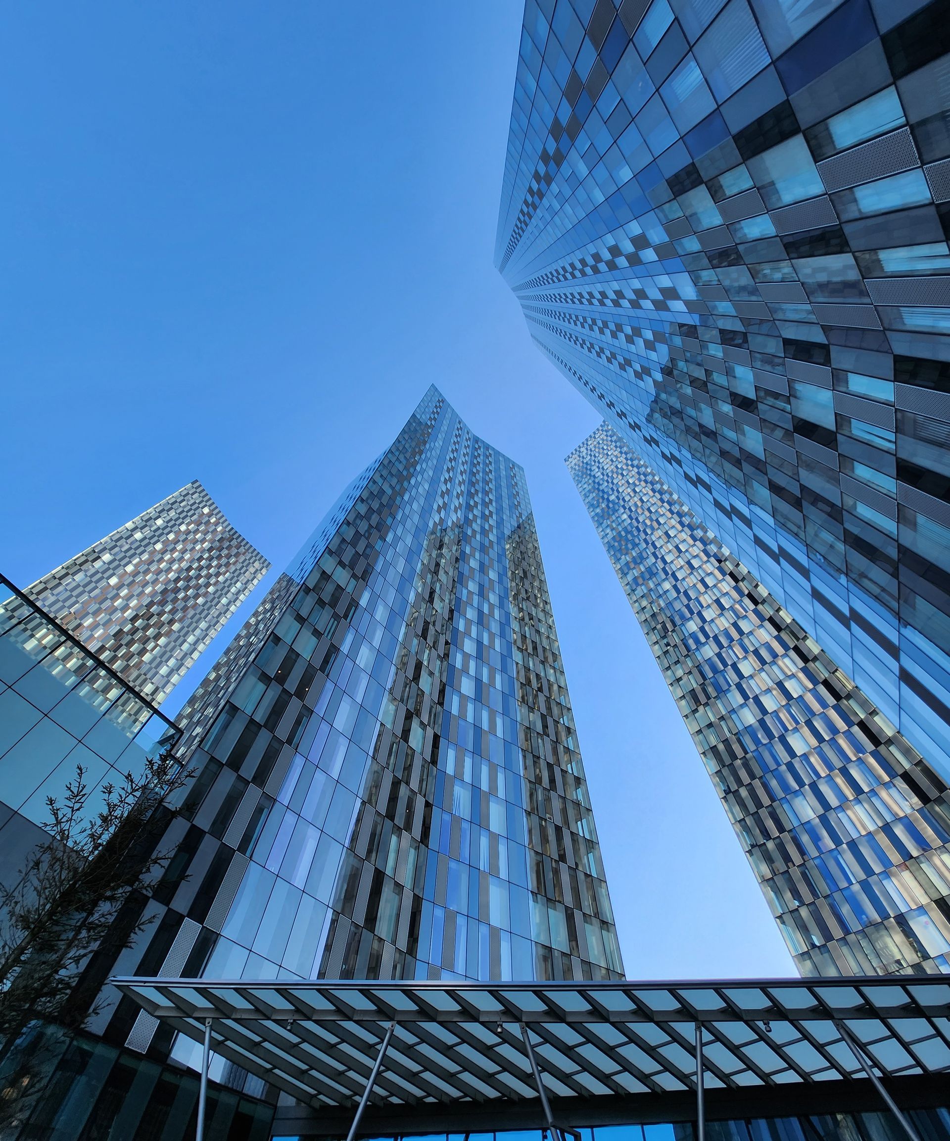 Skyscrapers with glass facades against a bright blue sky.