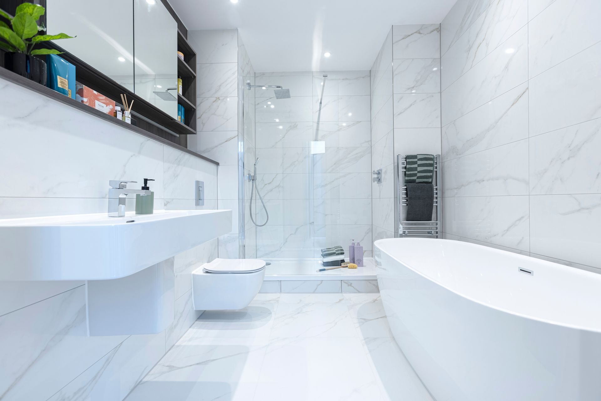 Modern white bathroom with a sink, toilet, shower, and freestanding tub.