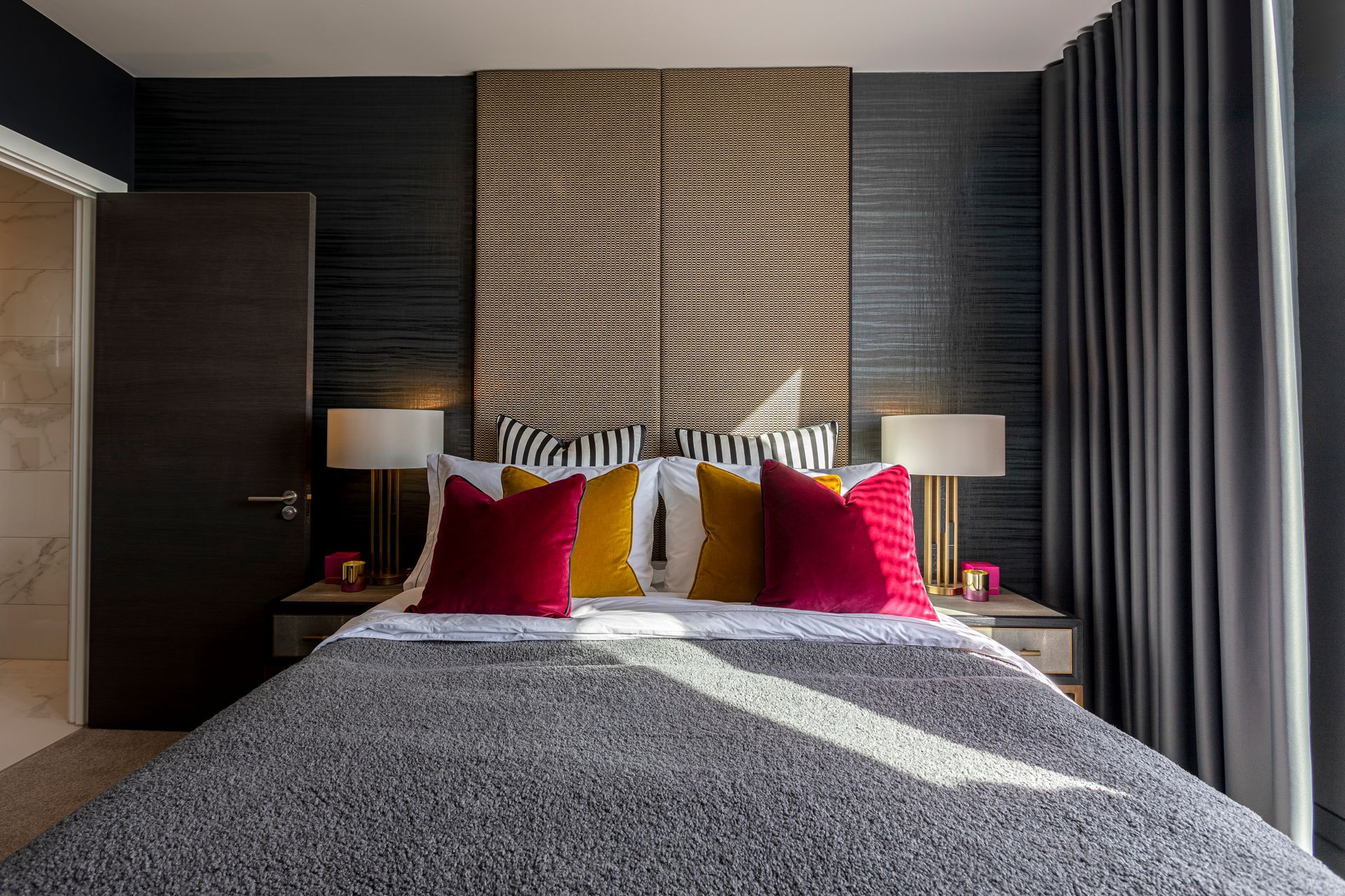 Bedroom with bed, headboard, dark wall, pillows, and side tables with lamps.