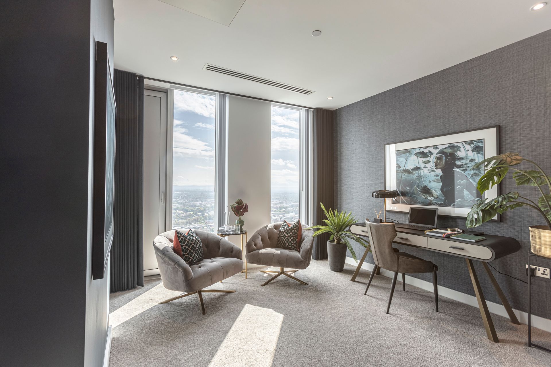 Modern office with gray walls, two chairs, a desk, and large windows with city view.