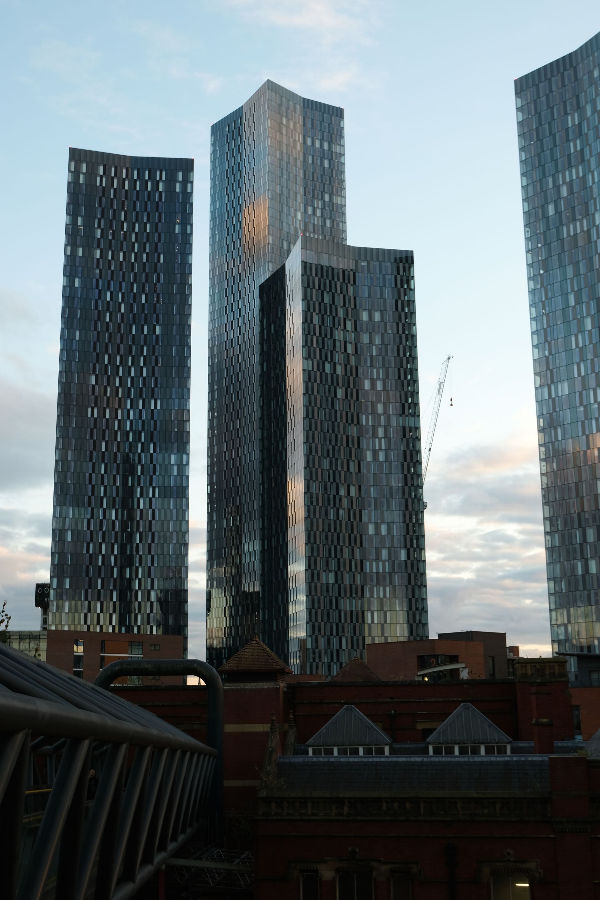 Tall modern skyscrapers against a cloudy sky, seen from a lower vantage point.