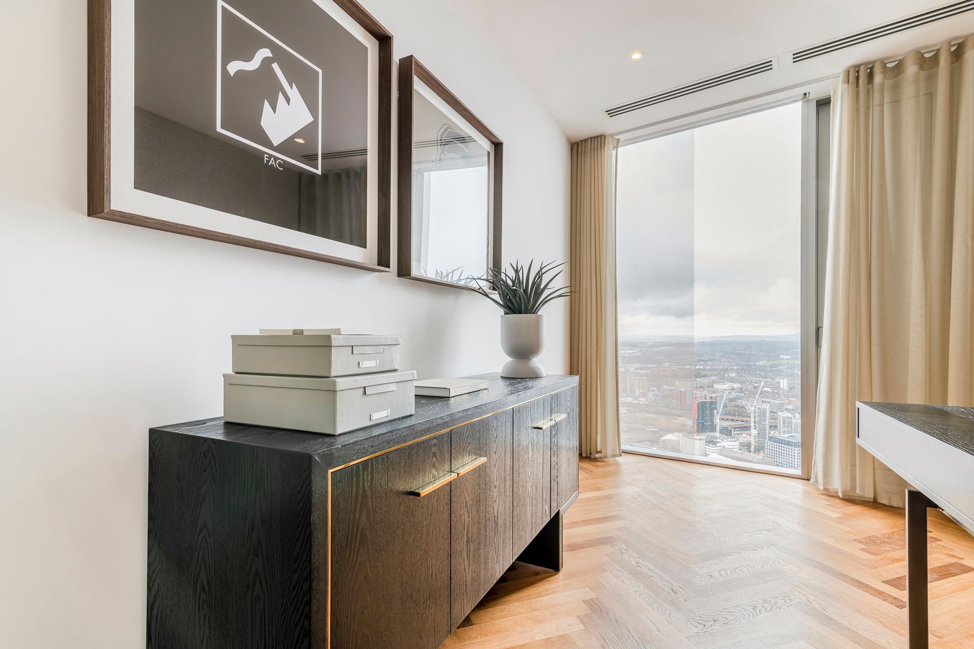 Modern living room with wooden floors, artwork, and a cityscape view.