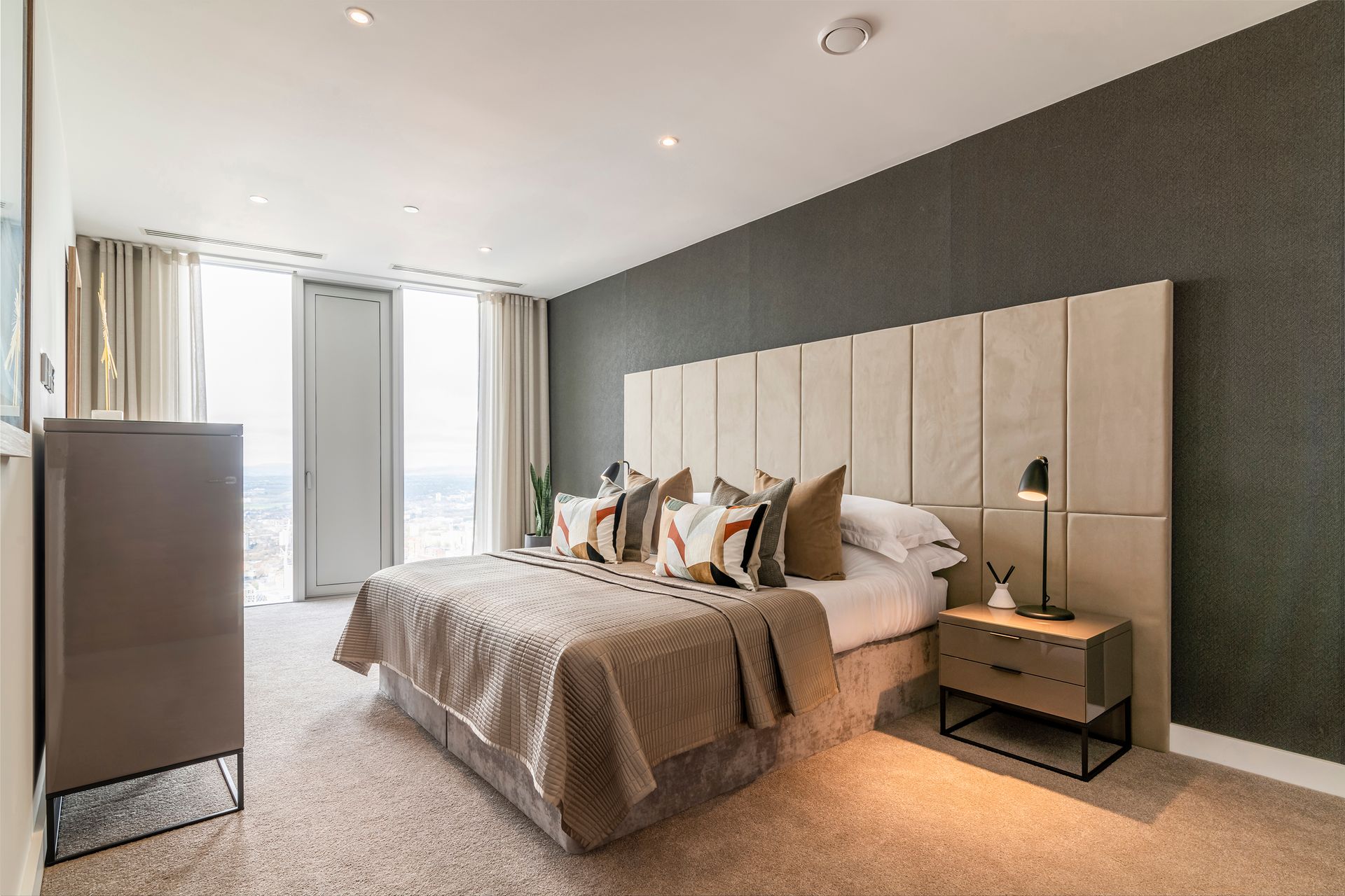 Bedroom with bed, headboard, nightstand, and window with curtains; neutral colors.