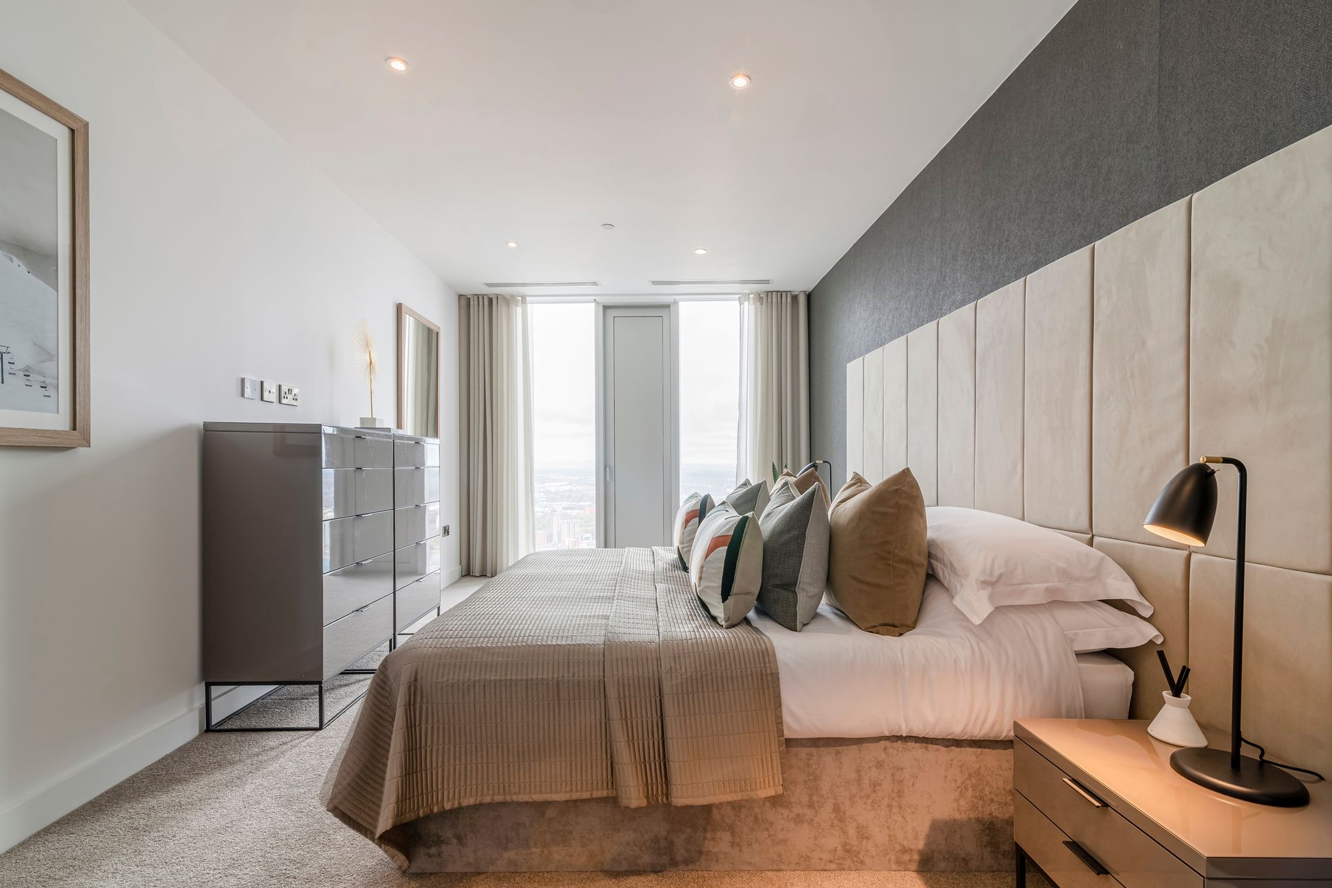 Bedroom with bed, neutral color scheme, upholstered headboard, bedside table, and window.
