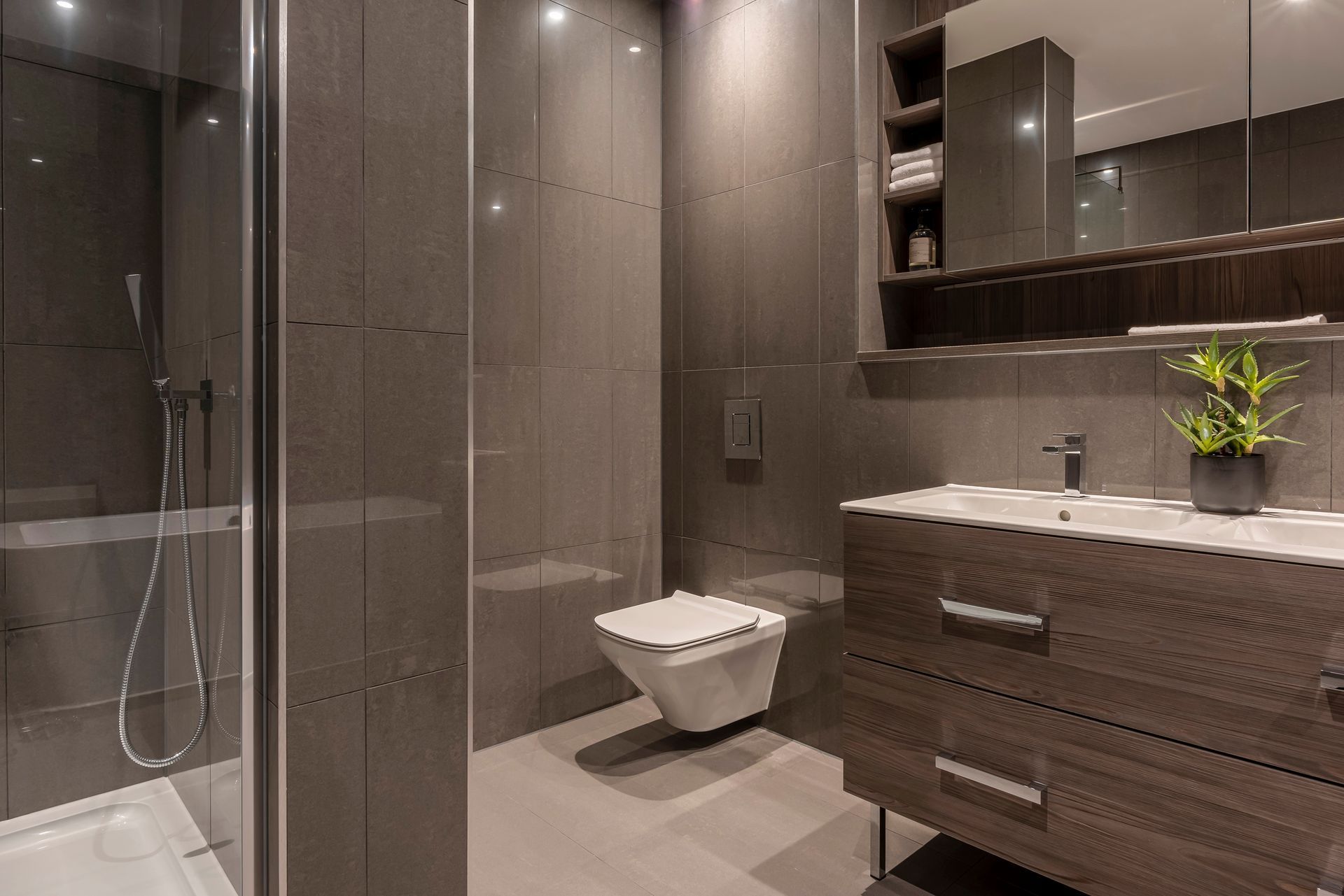 Modern gray bathroom with a shower, toilet, and vanity with a mirror.