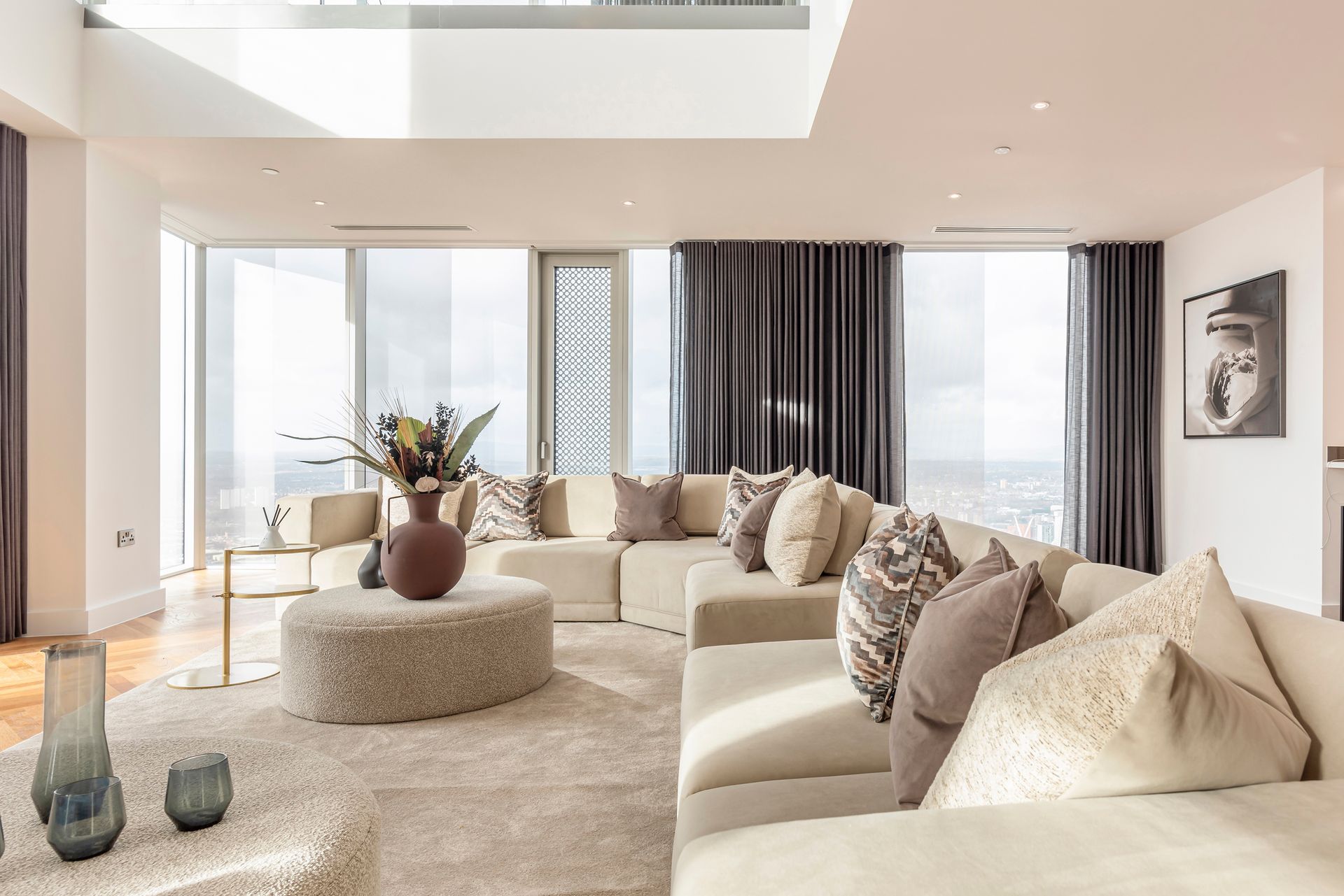 Modern living room with sectional sofa, large windows, and neutral color scheme.