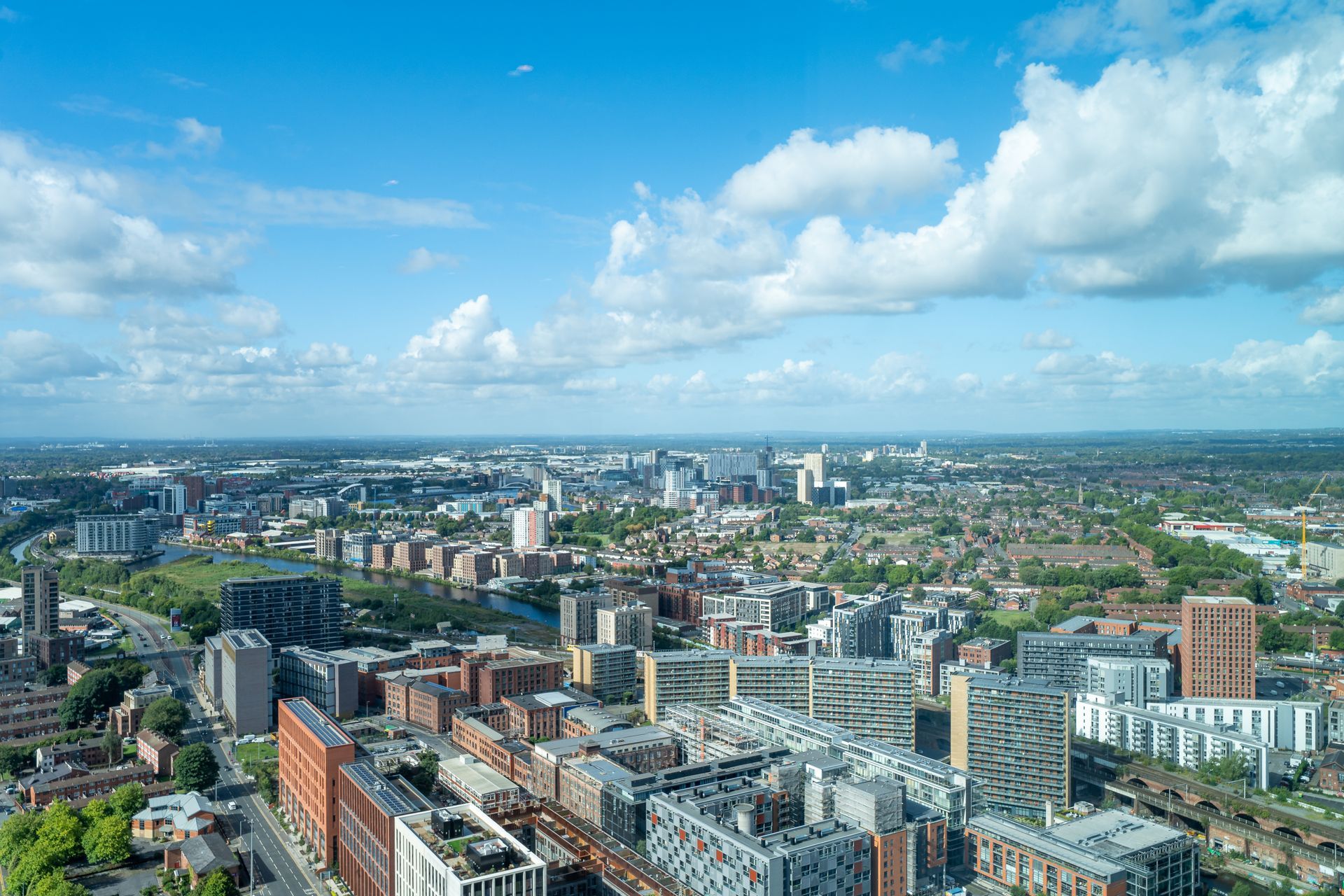 Cityscape with many buildings under a blue sky and fluffy clouds.
