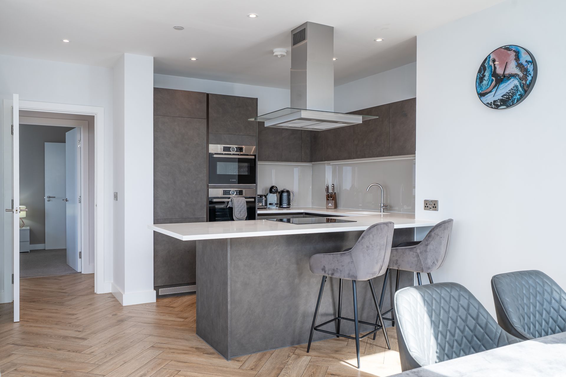 Modern kitchen with island, stainless steel appliances, and two bar stools.