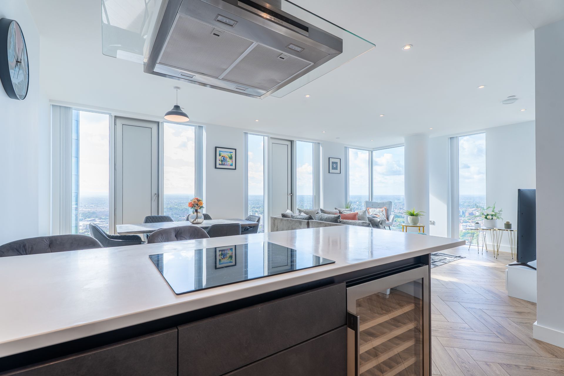 Modern open-plan kitchen and living space with city views, island, and large windows.
