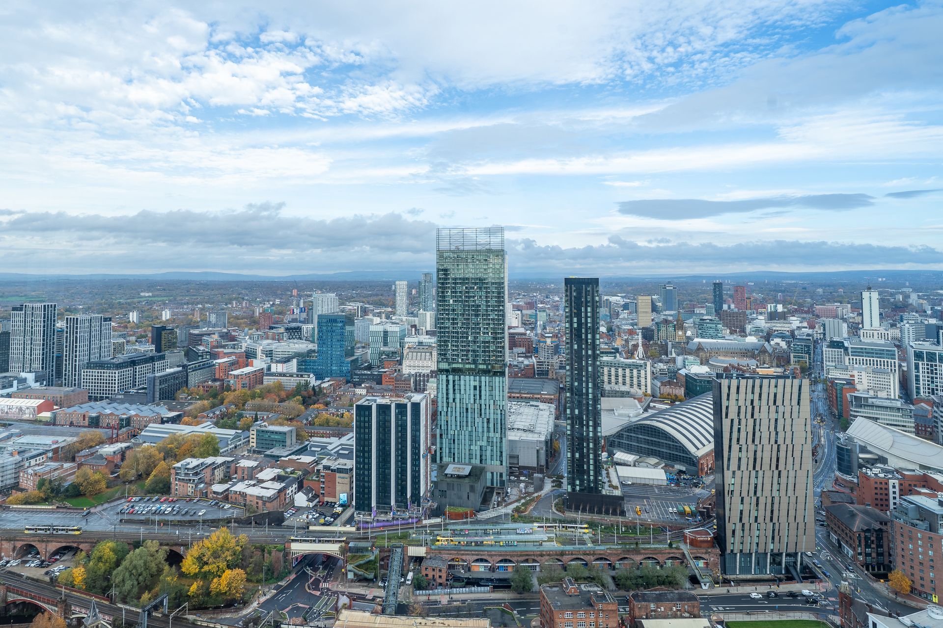 Aerial view of Manchester city skyline with skyscrapers and cloudy sky.