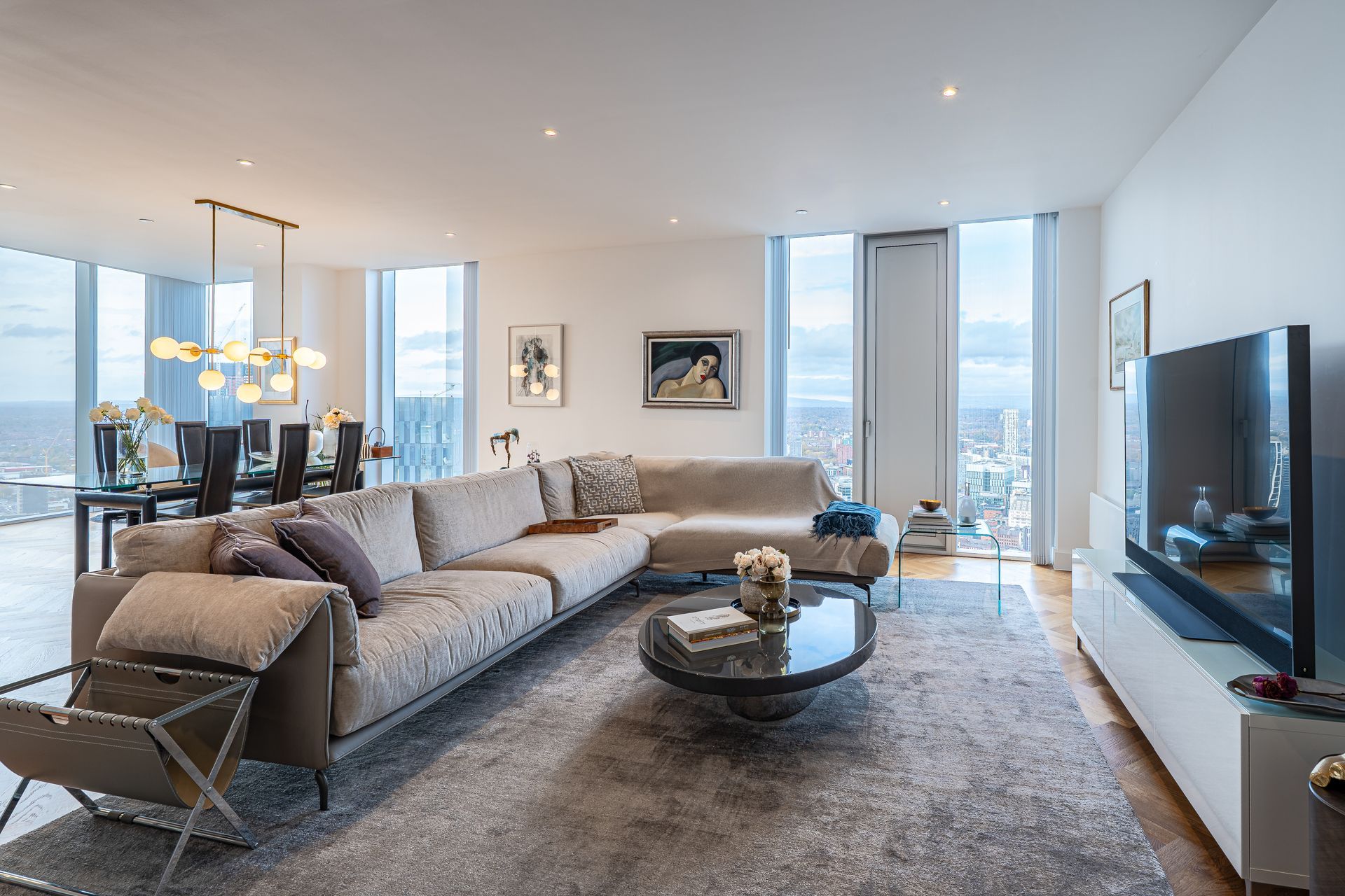 Spacious living room with sectional sofa, dining area, and city view from large windows.