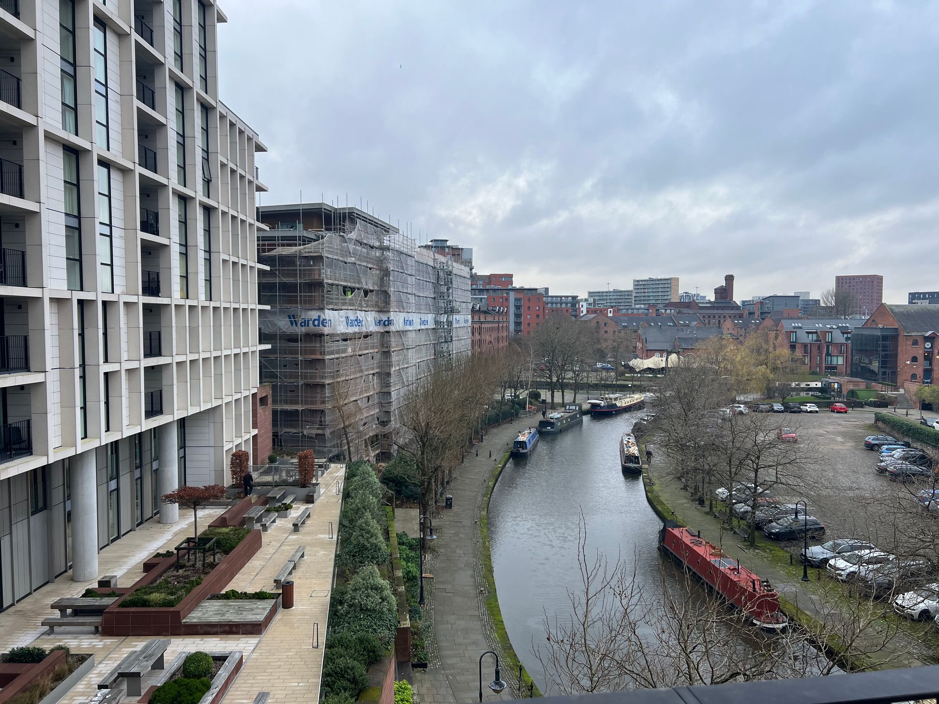 Cityscape with canal, apartment buildings, and cloudy sky.