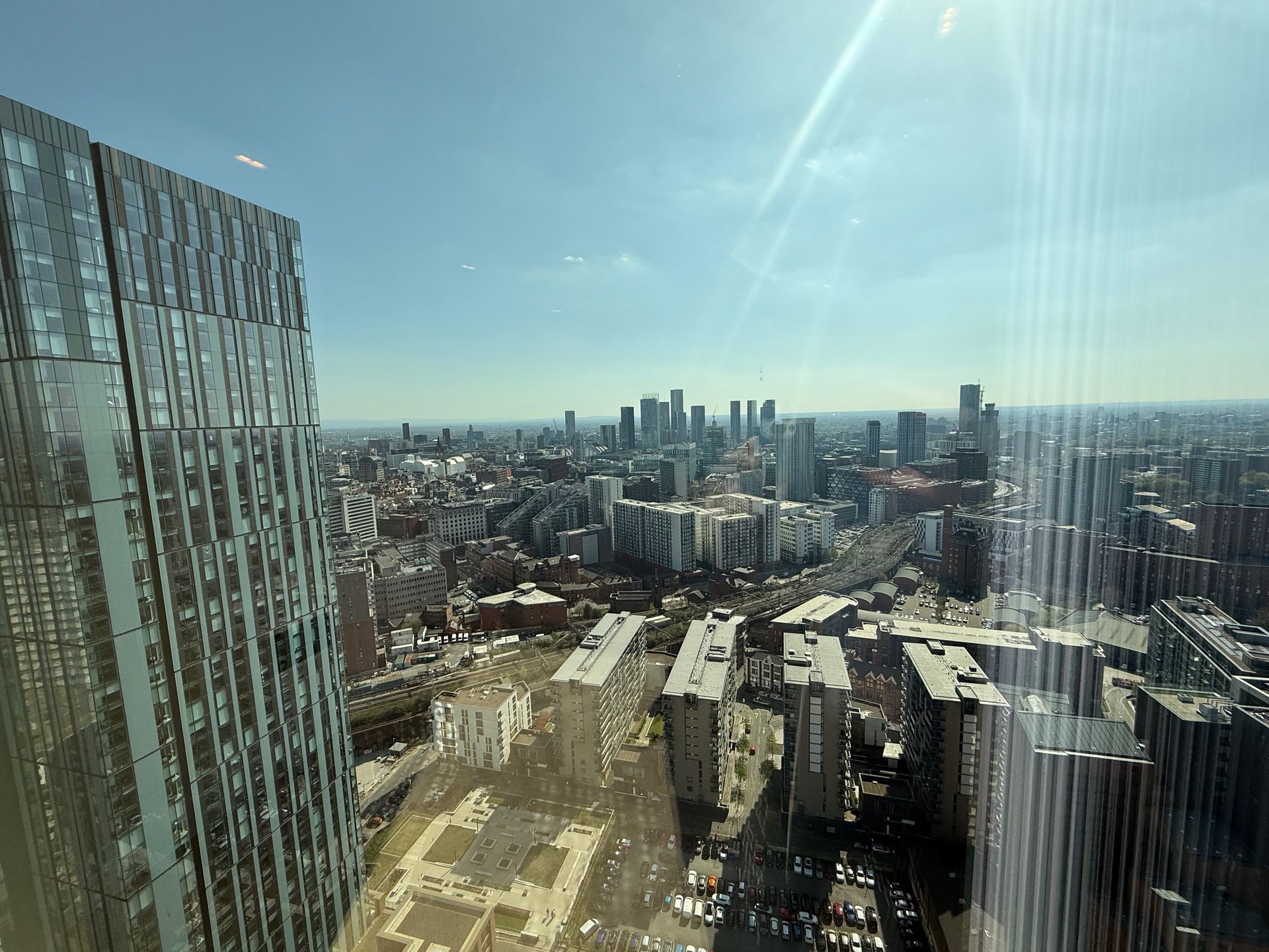 Cityscape view from a high-rise window on a sunny day, with modern skyscrapers and buildings visible.