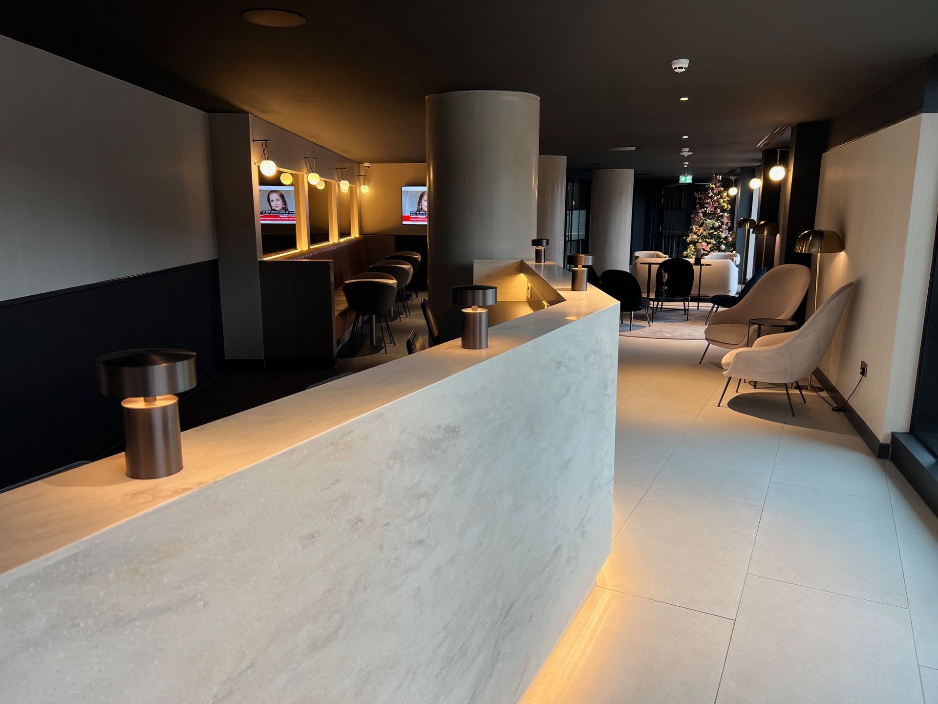 Modern hotel lobby with a curved counter, seating area, and neutral color palette.