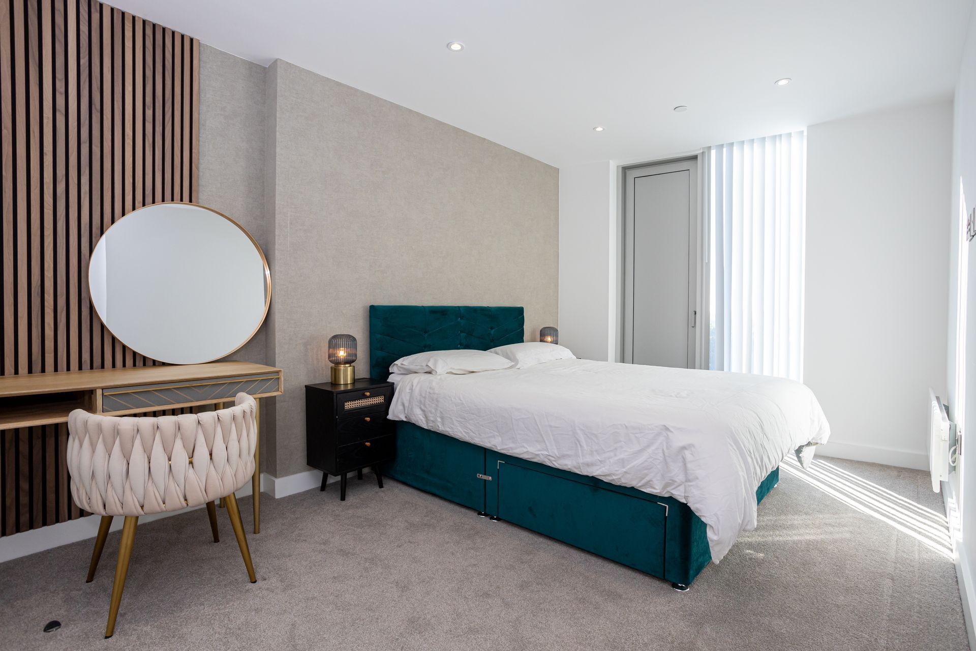 Bedroom with a teal bed, desk with a round mirror, and a wood-slat feature wall.