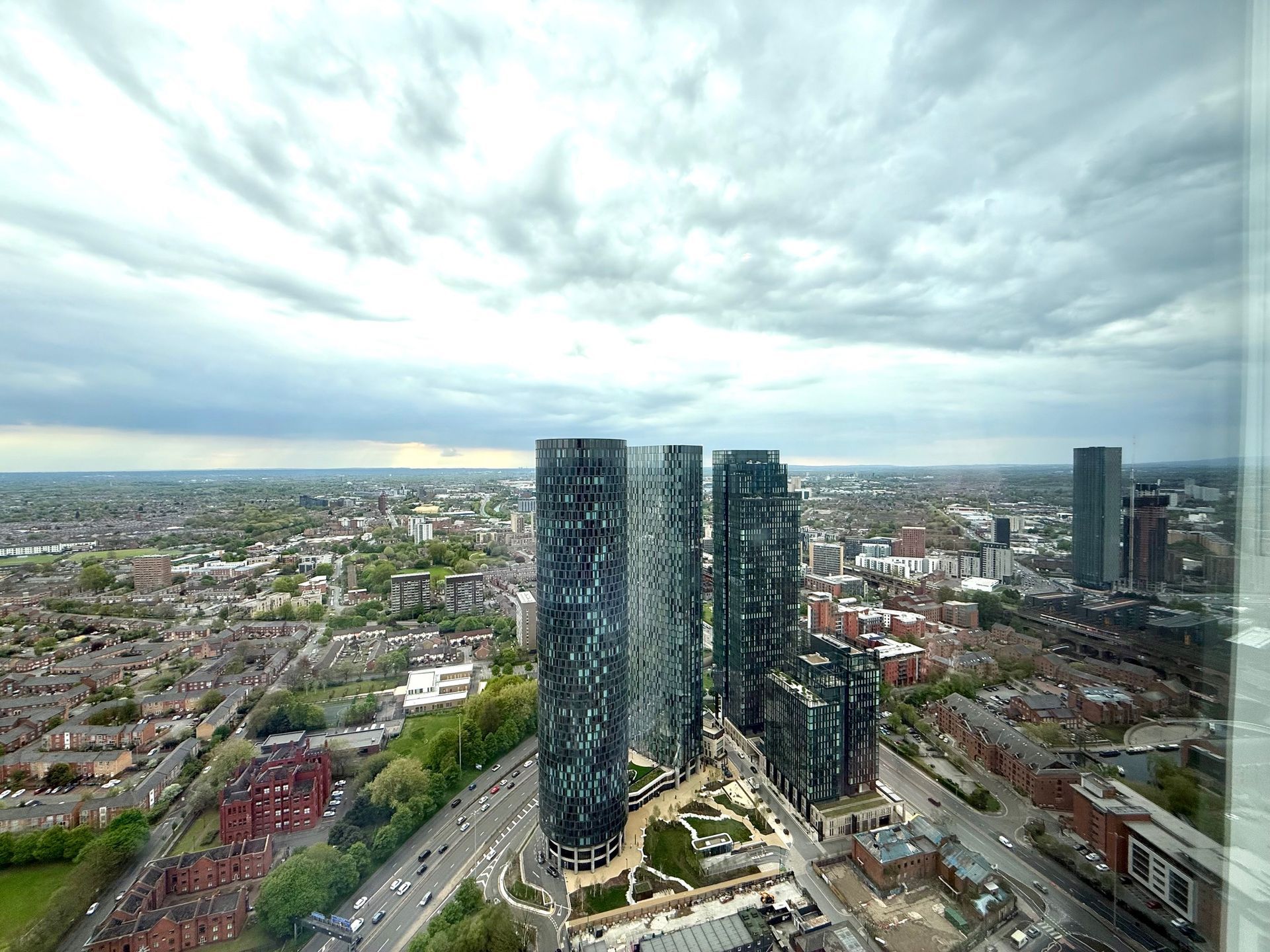 High-angle view of city with tall, modern skyscrapers under cloudy sky.